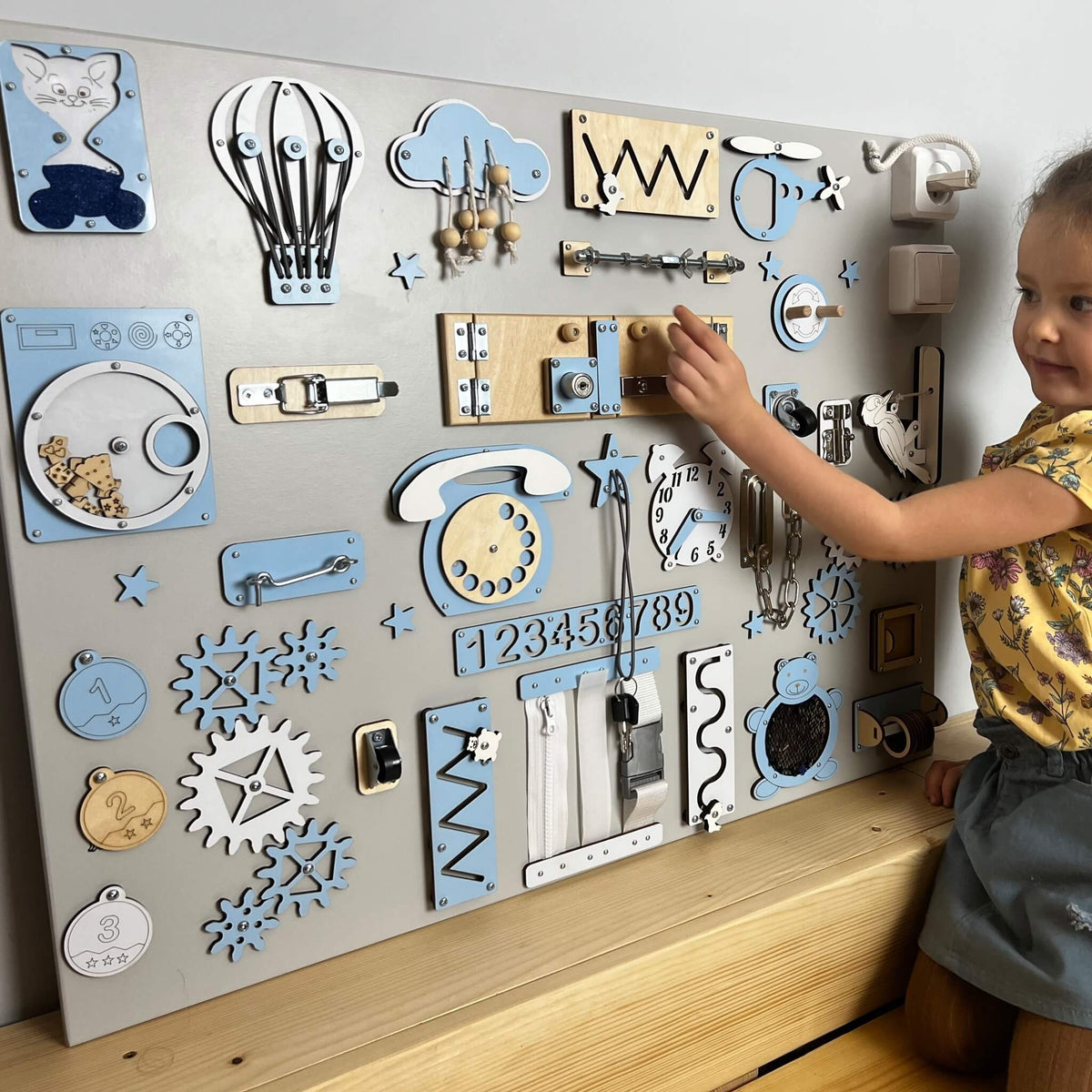 Holčička si hraje s extra velkým activity boardem na zeď BusyBunnyToys 60 × 80 cm, světle modré provedení
