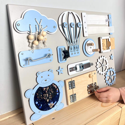 Dítě si hraje s malým activity boardem s dvířky BusyBunnyToys 30 × 40 cm, světle modré provedení