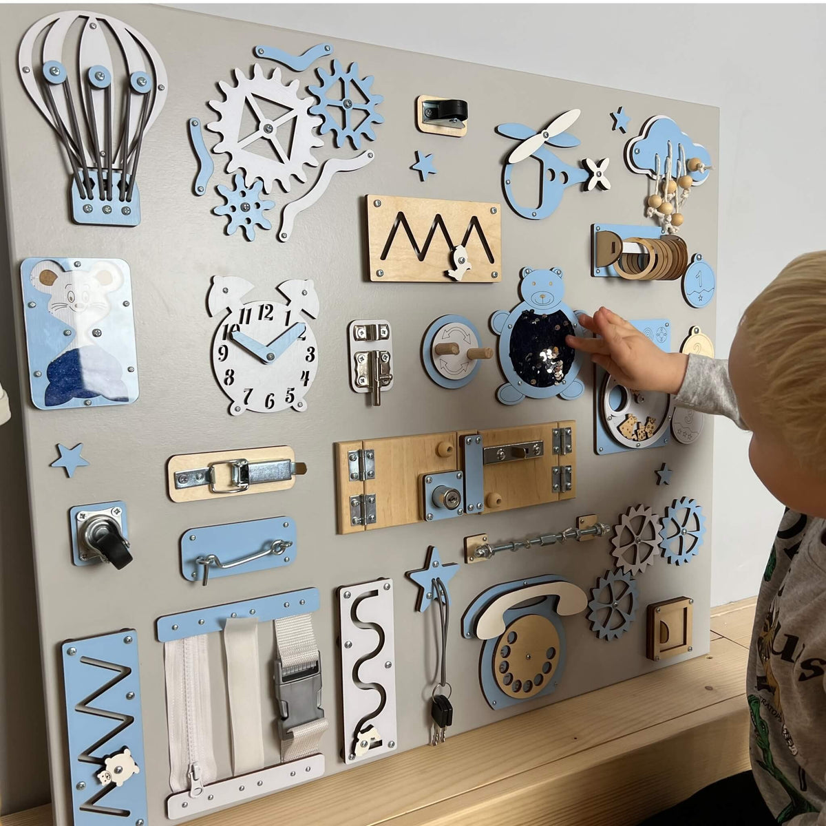 Dítě si hraje s velkým activity boardem na zeď BusyBunnyToys 60 × 70 cm, světle modré provedení