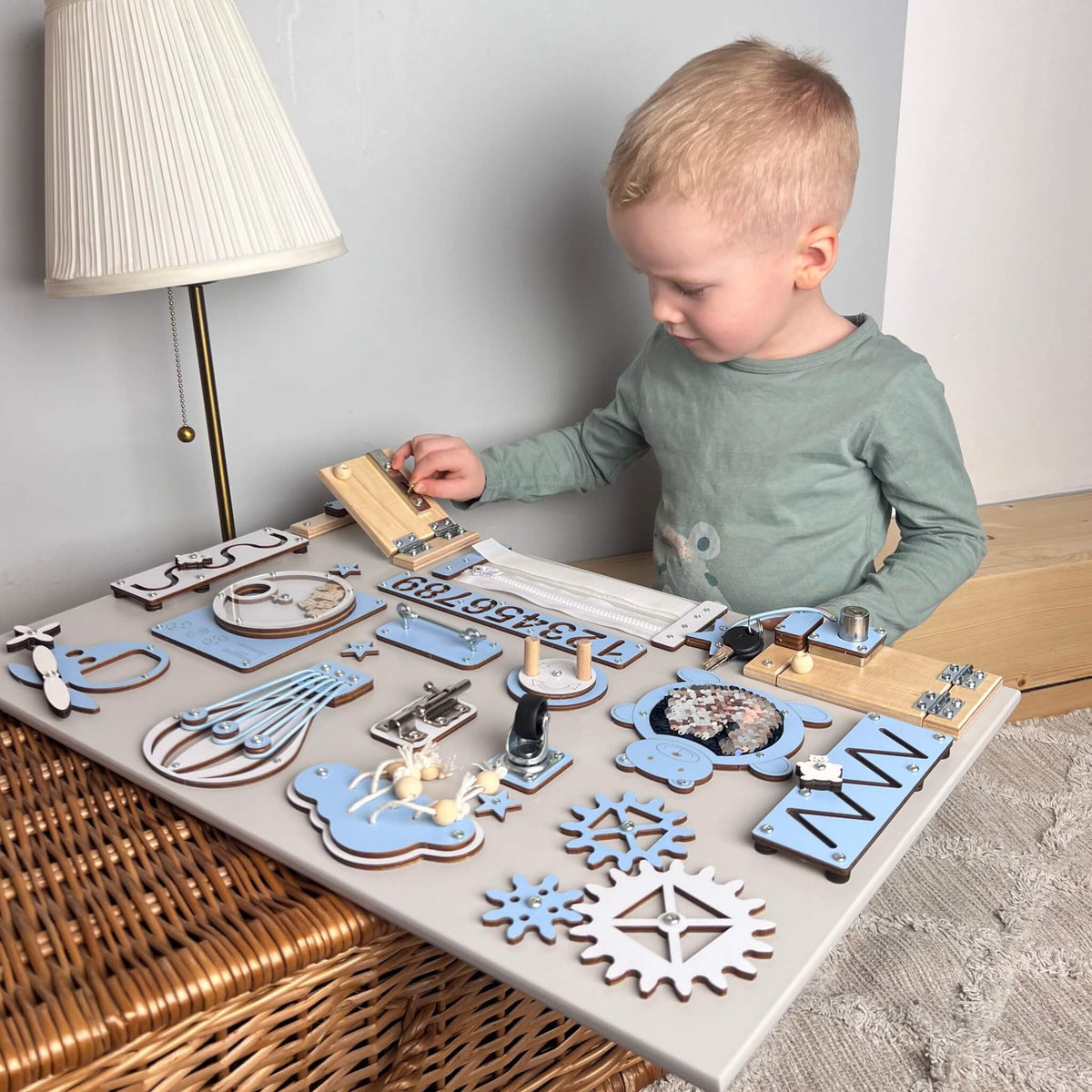 Chlapec si hraje s activity boardem s dvířky a zámky BusyBunnyToys 40 × 60 cm, světle modré provedení