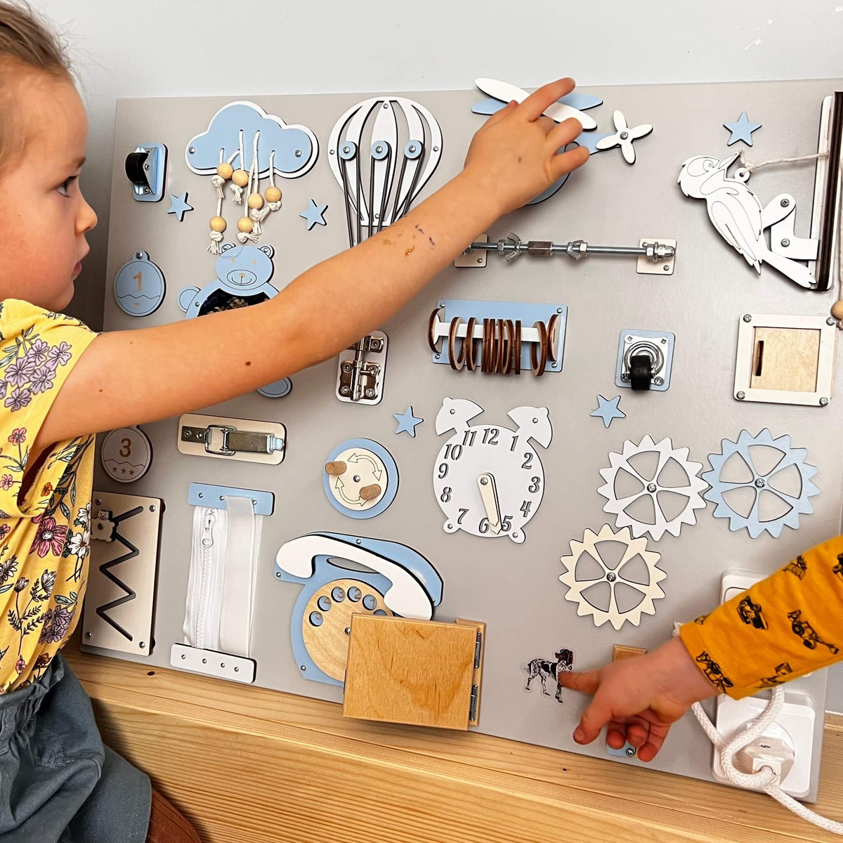 Děti si hrají s activity boardem na zeď BusyBunnyToys 50 × 60 cm, světle modré provedení